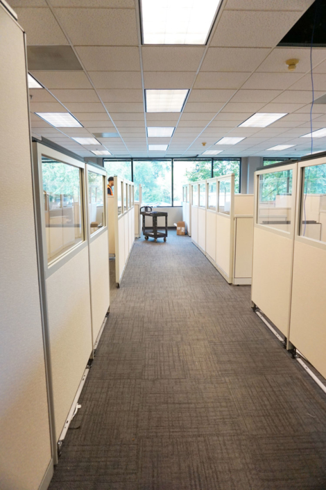 Office space with low height cubicle panels and white desk surfaces