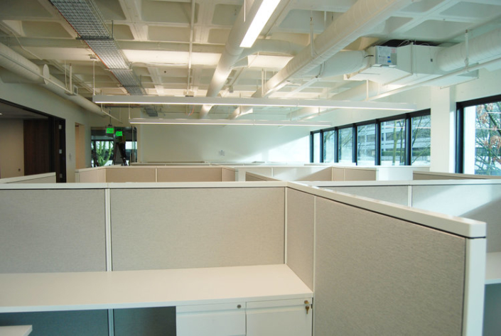 Office space with low height cubicle panels and white desk surfaces