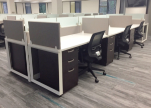 Modern work stations with white surfaces and dark wood storage