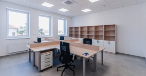 A small office with four desks arranged in a station, cabinets lining the back wall, and under-desk storage units.