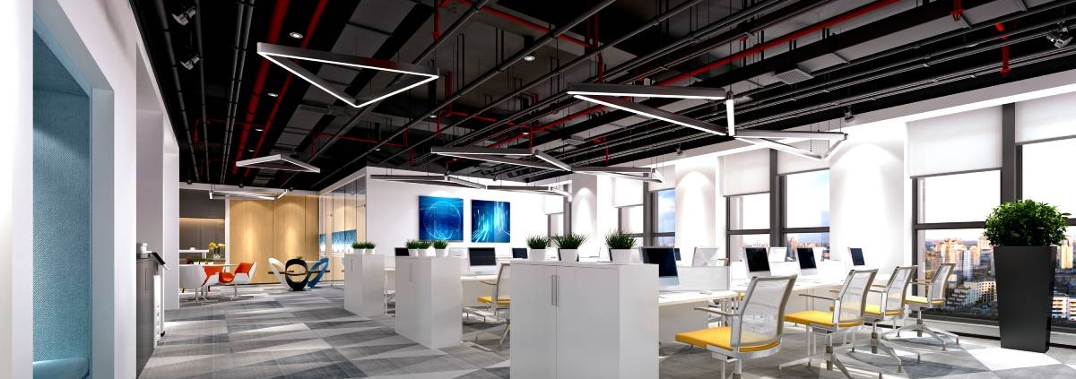 A modern office with open ceilings, carpeted floors, and rows of workstations with yellow chairs. Some windows show a city view.