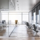 An office that has a row of desks, chairs, and monitors. There's an area with a large table and multiple chairs.