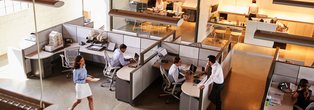 An aerial view of an open office space. There are people doing work in different areas of the office.