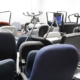 Multiple black, blue, and red office chairs are crowded in a brightly lit storage room with white walls.