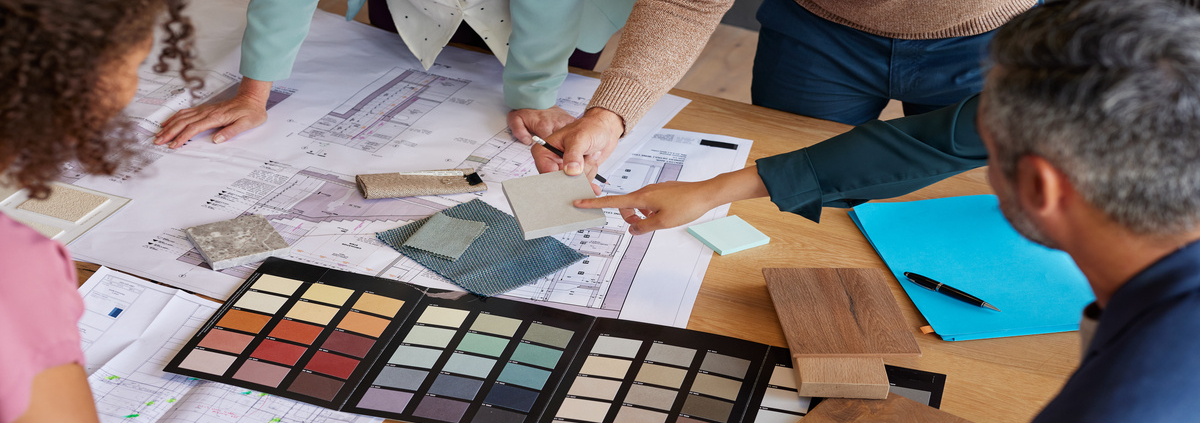 A team of designers examines material samples and color swatches to finalize design plans for a project.