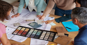 A team of designers examines material samples and color swatches to finalize design plans for a project.