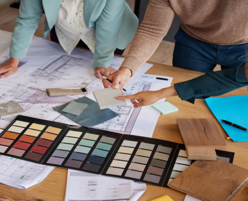 A team of designers examines material samples and color swatches to finalize design plans for a project.