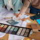 A team of designers examines material samples and color swatches to finalize design plans for a project.