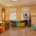 Two coworkers arrange colorful modular chairs at multiple desks in a brightly lit office workspace.