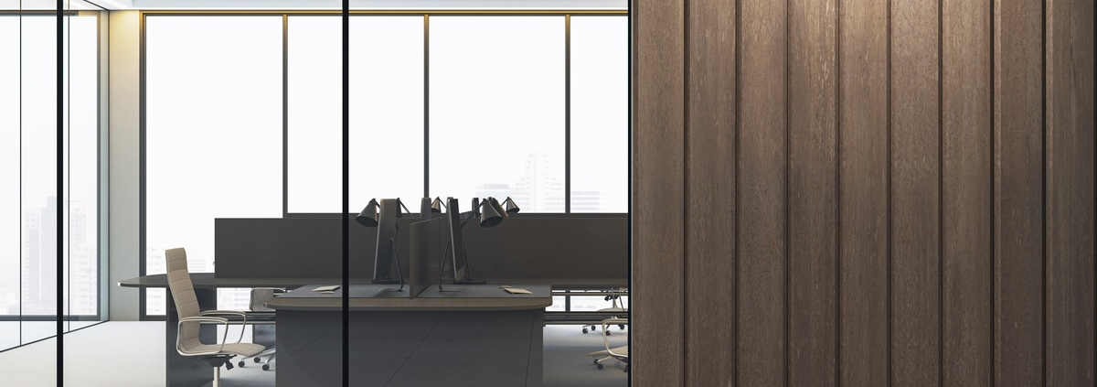 An office interior featuring glass walls, wooden panel accents, and minimalist workstations in a high-rise building.