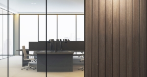 An office interior featuring glass walls, wooden panel accents, and minimalist workstations in a high-rise building.