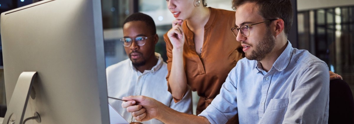 A diverse team is working in the office on a computer during a night workshop for business planning and strategy.