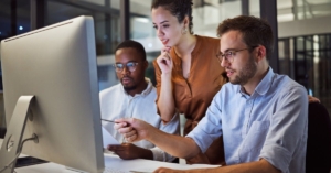 A diverse team is working in the office on a computer during a night workshop for business planning and strategy.