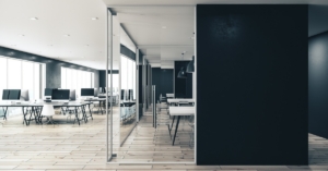 A medium-sized startup business office with a modern design and a private glass conference room in the middle.