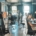 Busy office scene with professionals typing on laptops, meeting and moving through bright open-plan workspace.