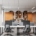 Contemporary workspace with shared desks, computer screens, office chairs, and built-in wooden cabinets and bookshelves.